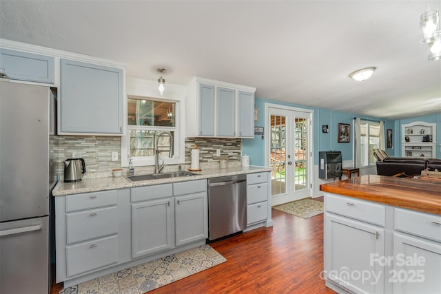kitchen with dark wood-style floors, stainless steel appliances, backsplash, a sink, and butcher block counters