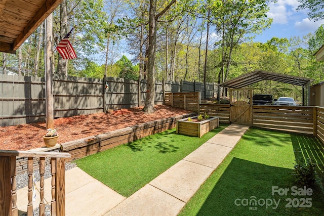 view of yard featuring a gate, fence, and a carport