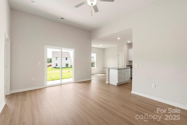unfurnished living room featuring baseboards, light wood-style floors, and a ceiling fan