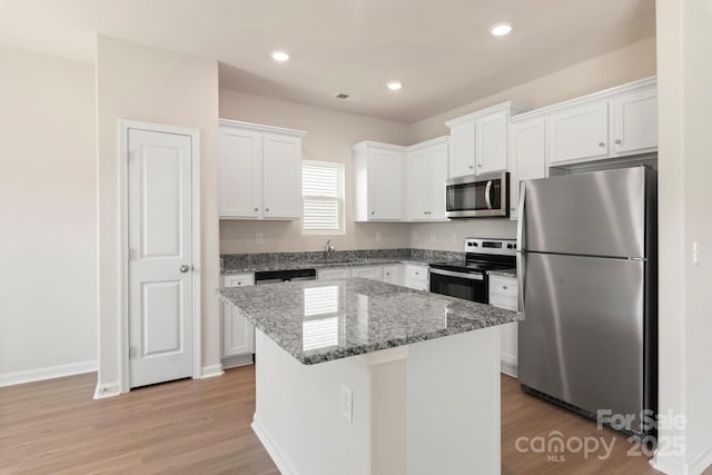 kitchen with a center island, light stone counters, recessed lighting, white cabinets, and stainless steel appliances