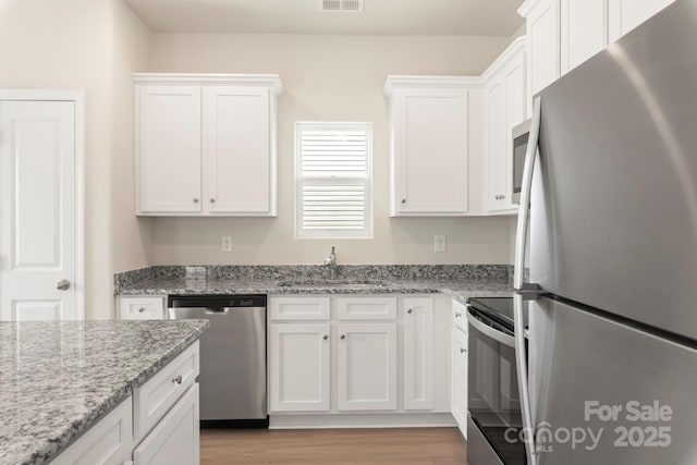 kitchen featuring visible vents, white cabinets, appliances with stainless steel finishes, and a sink
