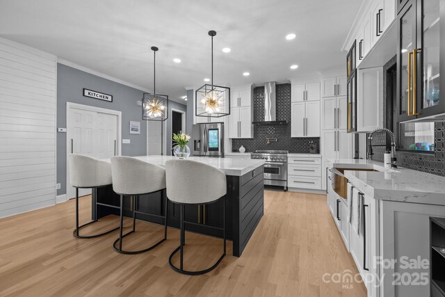 15921 Cramur Dr, Huntersville, NC 28078 - kitchen featuring light wood finished floors, tasteful backsplash, appliances with stainless steel finishes, a sink, and wall chimney range hood