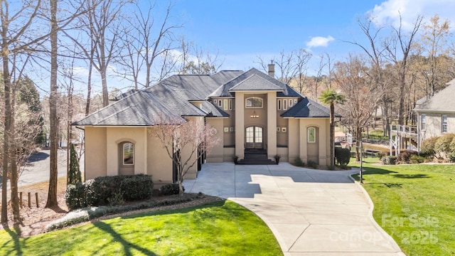 french country style house featuring stucco siding, driveway, and a front yard