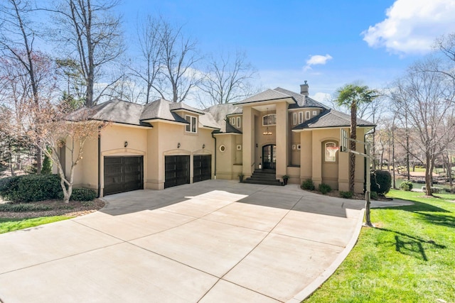 mediterranean / spanish home with stucco siding, driveway, a front yard, a garage, and a chimney