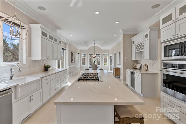 kitchen with a notable chandelier, wine cooler, a sink, appliances with stainless steel finishes, and a center island