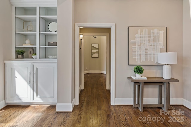 corridor featuring baseboards and wood finished floors