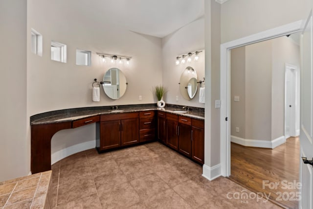 bathroom featuring baseboards, double vanity, and a sink