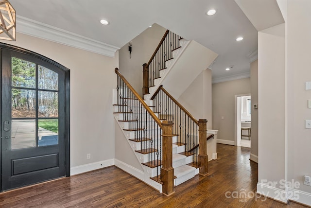 foyer with ornamental molding, dark wood-type flooring, stairway, and baseboards