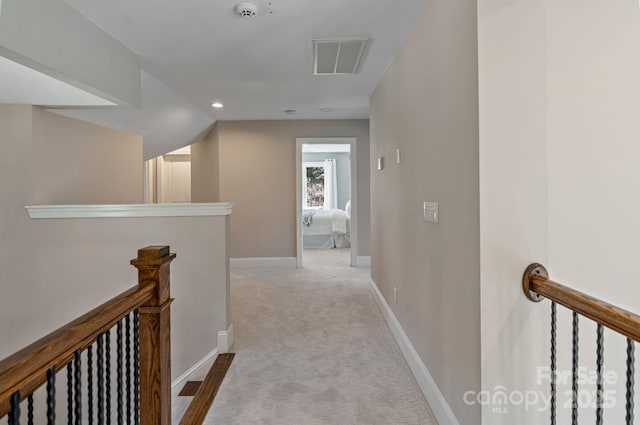 corridor with an upstairs landing, lofted ceiling, baseboards, visible vents, and light carpet