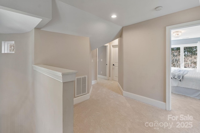 hallway featuring light carpet, baseboards, visible vents, and recessed lighting