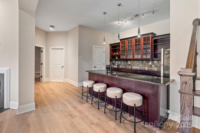 bar featuring baseboards, backsplash, a sink, light wood-style floors, and freestanding refrigerator