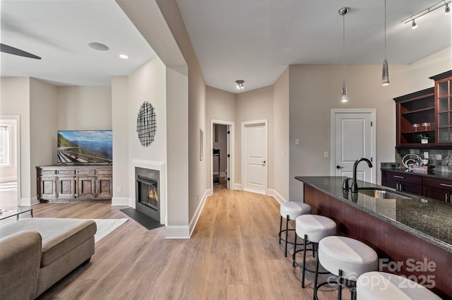 kitchen with dark stone counters, a kitchen bar, a sink, and light wood-style floors