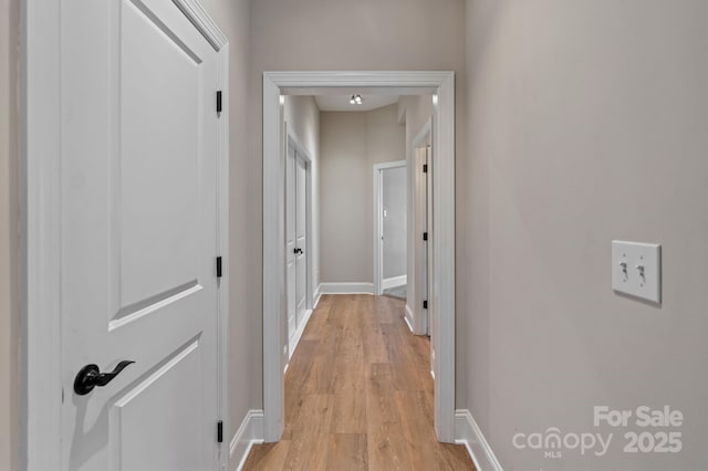 corridor featuring baseboards and light wood-type flooring