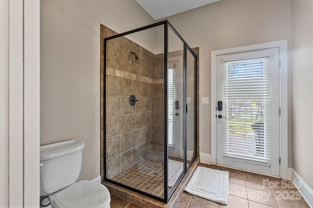 bathroom featuring a stall shower, baseboards, toilet, and tile patterned flooring