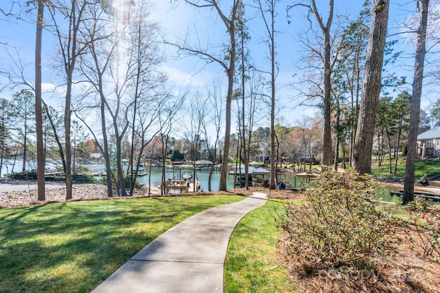 surrounding community with a water view, a boat dock, and a yard