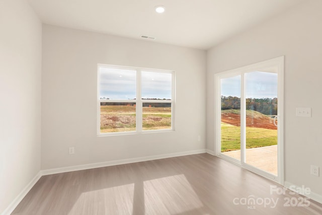 spare room with visible vents, baseboards, a healthy amount of sunlight, and wood finished floors