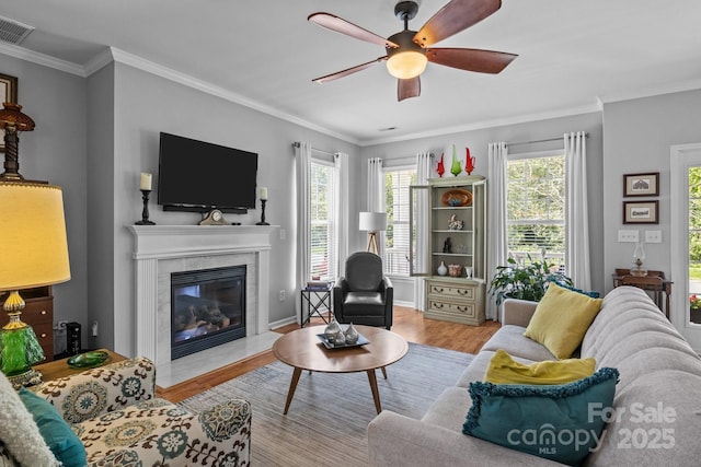 living room with ceiling fan, a wealth of natural light, wood finished floors, and a fireplace
