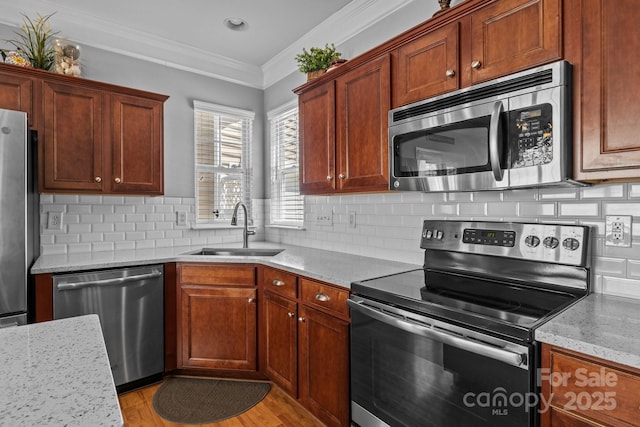 kitchen with crown molding, tasteful backsplash, a sink, stainless steel appliances, and light wood-style flooring