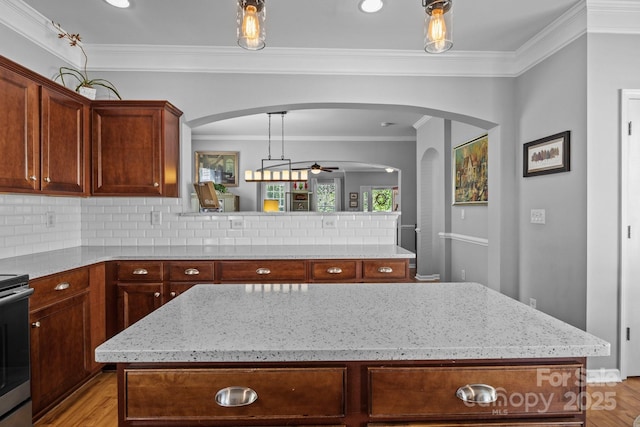 kitchen featuring a ceiling fan, light stone counters, light wood-style floors, and ornamental molding