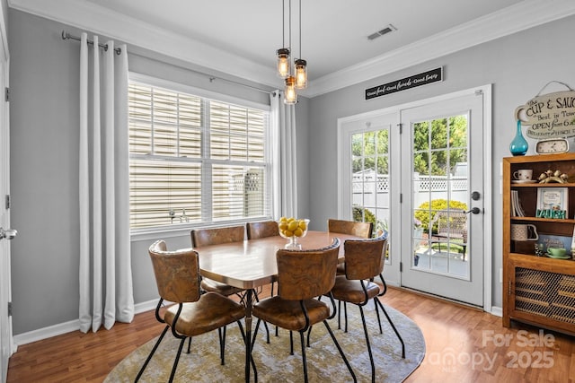 dining area with baseboards, crown molding, visible vents, and light wood-type flooring