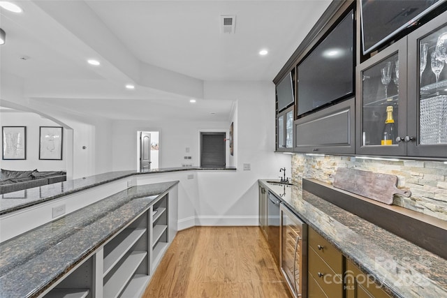 kitchen with visible vents, baseboards, tasteful backsplash, a sink, and light wood-type flooring