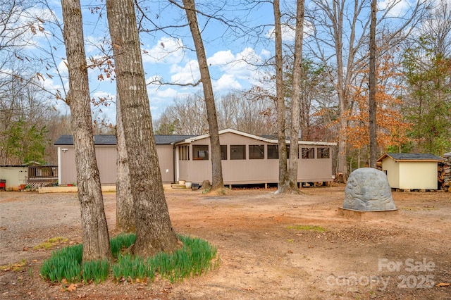view of front facade featuring an outdoor structure, a sunroom, and a storage unit