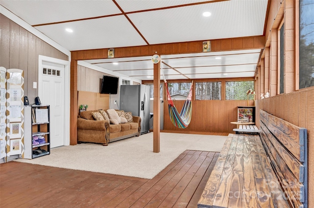 living area with wooden walls, wood finished floors, and carpet