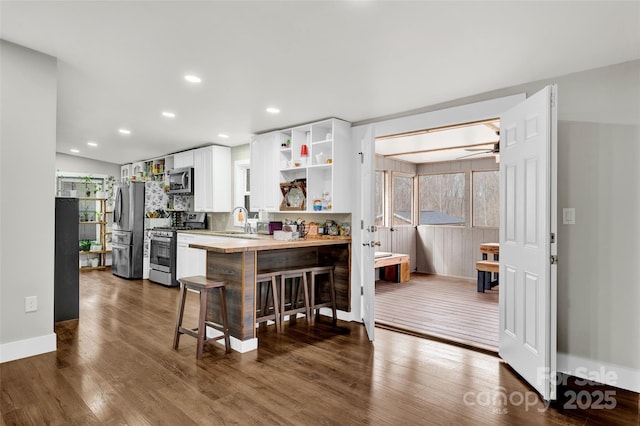 kitchen with a kitchen breakfast bar, white cabinetry, open shelves, dark wood-style flooring, and appliances with stainless steel finishes