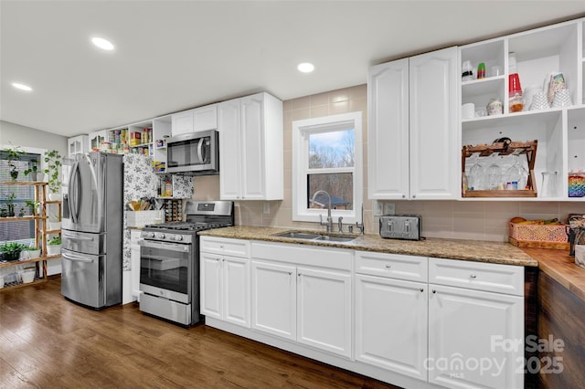 kitchen featuring dark wood-type flooring, a sink, appliances with stainless steel finishes, and open shelves
