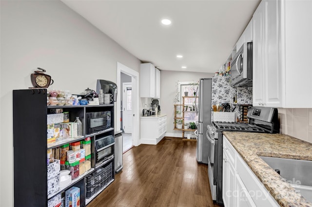 kitchen with stainless steel appliances, dark wood finished floors, backsplash, light stone counters, and white cabinets