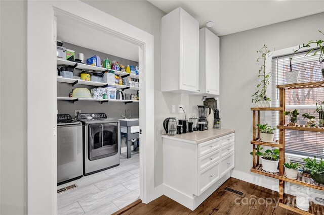 laundry area with wood finished floors, washing machine and dryer, laundry area, and visible vents
