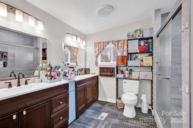 full bath featuring a stall shower, double vanity, toilet, and a sink