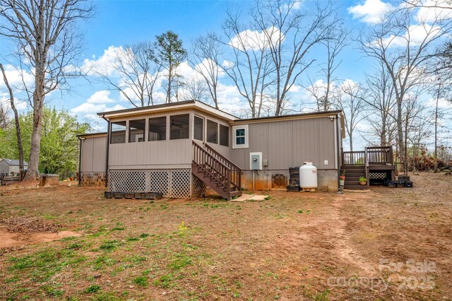 rear view of property featuring a sunroom, a deck, and stairway