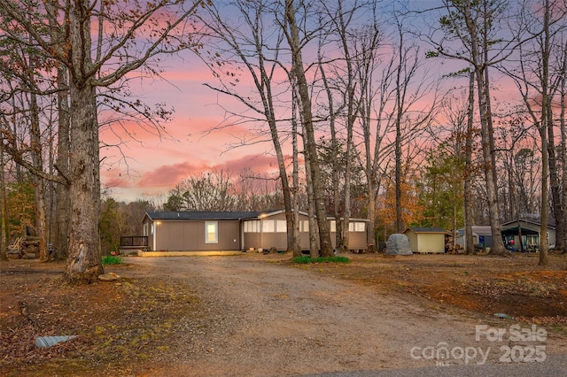 view of front of house featuring a storage unit, driveway, and an outbuilding