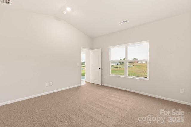 carpeted spare room featuring lofted ceiling, baseboards, and visible vents