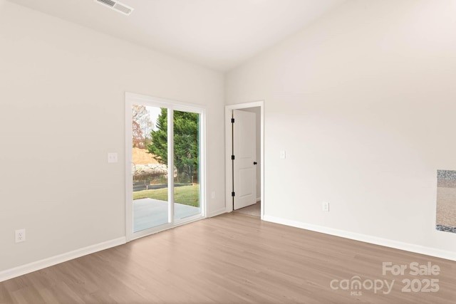 empty room featuring visible vents, baseboards, and wood finished floors