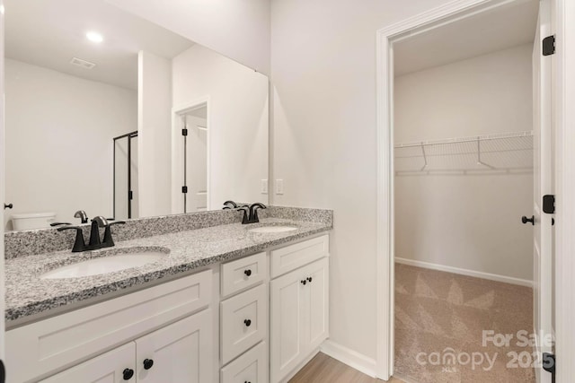 bathroom featuring a sink, visible vents, a walk in closet, and double vanity