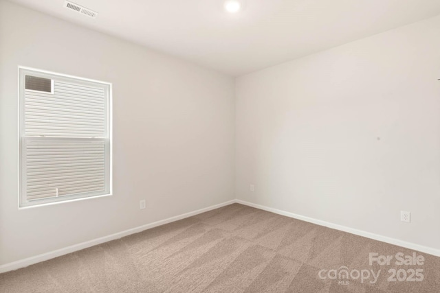 unfurnished room with visible vents, baseboards, and light colored carpet