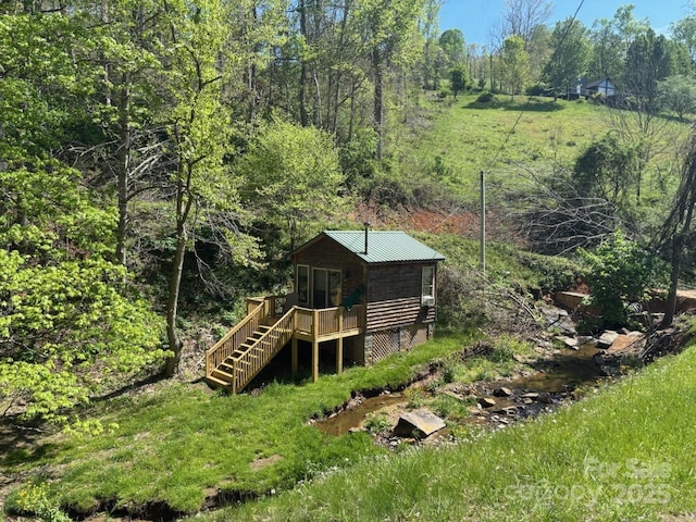 exterior space with a wooden deck, stairway, and a wooded view