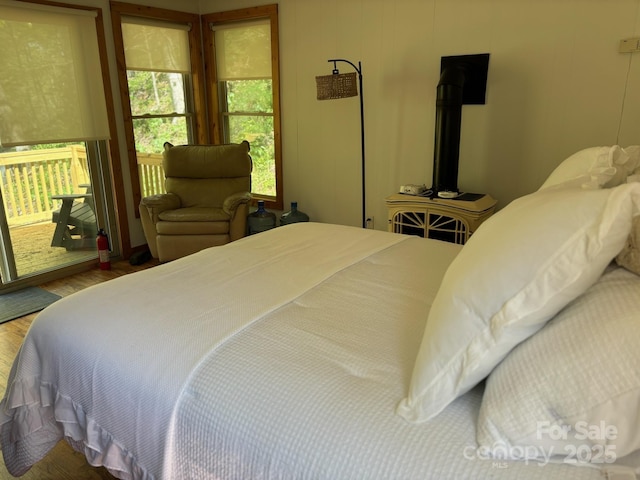 bedroom featuring a wood stove, wood finished floors, and access to outside
