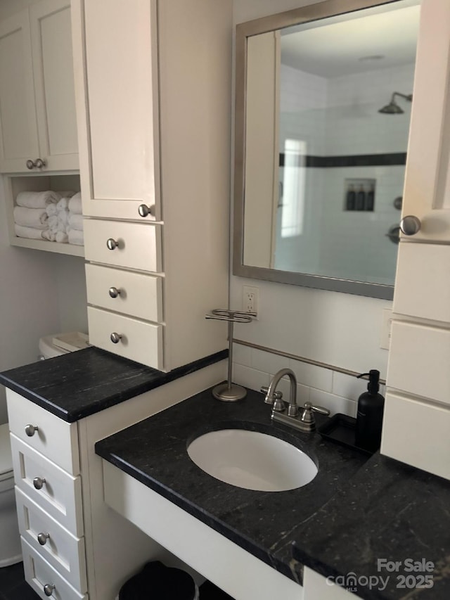 bathroom featuring vanity, toilet, and decorative backsplash