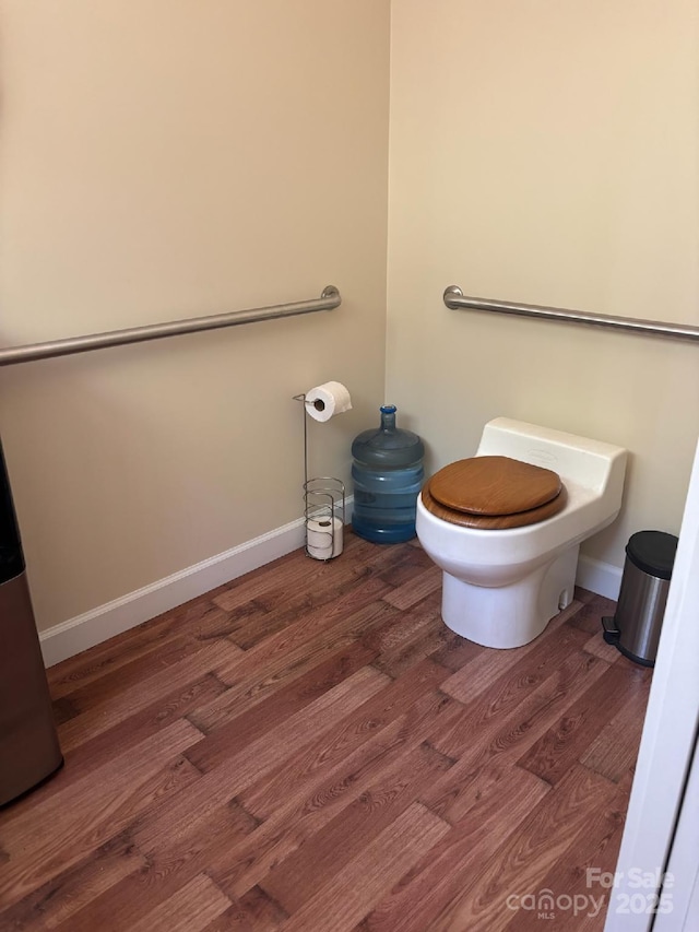bathroom featuring baseboards, wood finished floors, and toilet