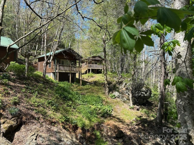 view of yard featuring a wooden deck and a view of trees
