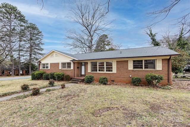 ranch-style home featuring brick siding, a front lawn, and roof with shingles