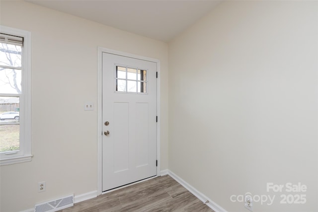 foyer entrance with visible vents, plenty of natural light, and light wood-style flooring