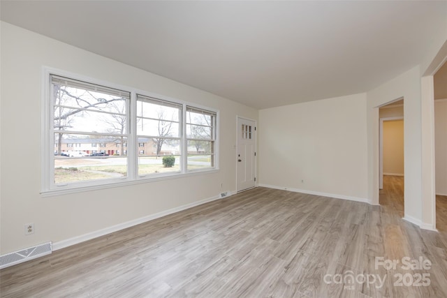 unfurnished living room featuring baseboards, visible vents, and light wood-type flooring