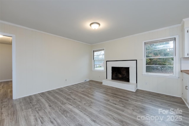 unfurnished living room with a fireplace, light wood-style floors, and ornamental molding