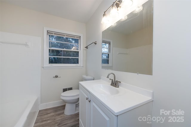 full bath with visible vents, toilet, wood finished floors, baseboards, and vanity