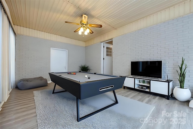 playroom with a ceiling fan, light wood-type flooring, and brick wall