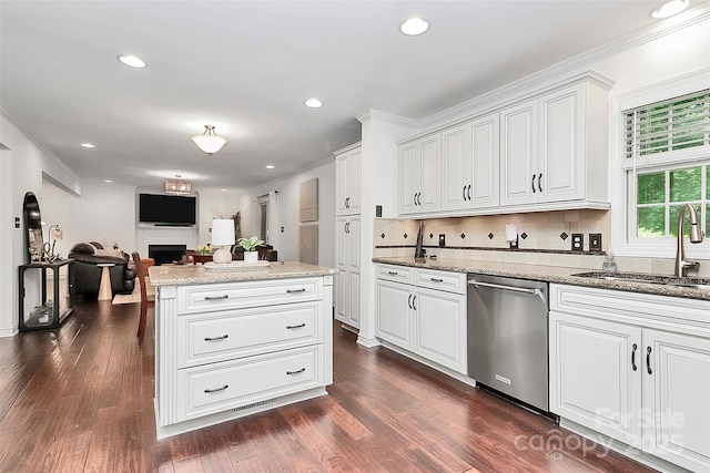 kitchen featuring white cabinets, a sink, a fireplace, tasteful backsplash, and stainless steel dishwasher